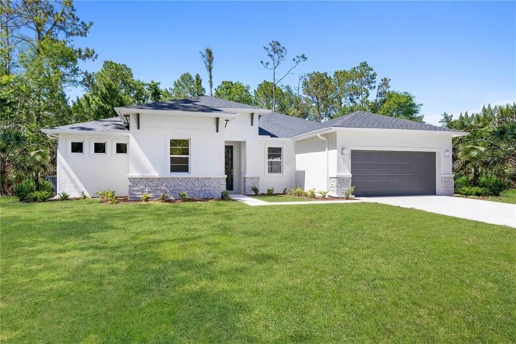 74 Uhl Path, Palm Coast, FL 32164 - prairie-style home with concrete driveway, a front lawn, an attached garage, and stucco siding