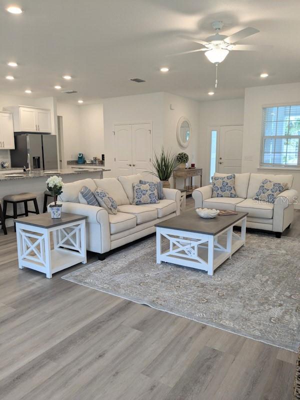 living room with light hardwood / wood-style floors and ceiling fan