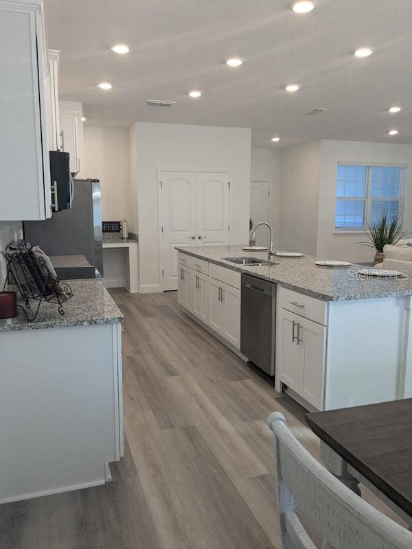 kitchen featuring light hardwood / wood-style floors, stainless steel dishwasher, white cabinetry, and sink