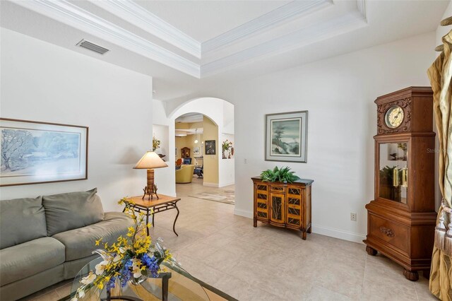 living room featuring crown molding, a raised ceiling, and light tile patterned floors