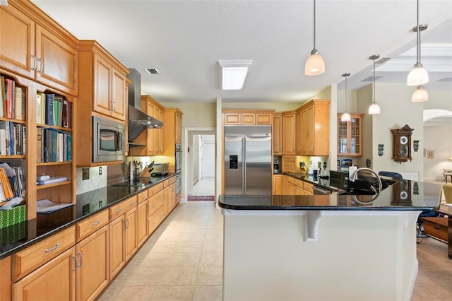 kitchen featuring built in appliances, decorative light fixtures, kitchen peninsula, light tile patterned flooring, and wall chimney range hood