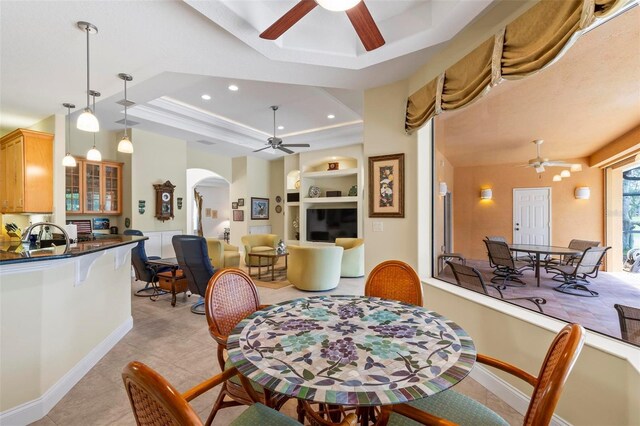 dining area with a raised ceiling, ceiling fan, and light tile patterned floors