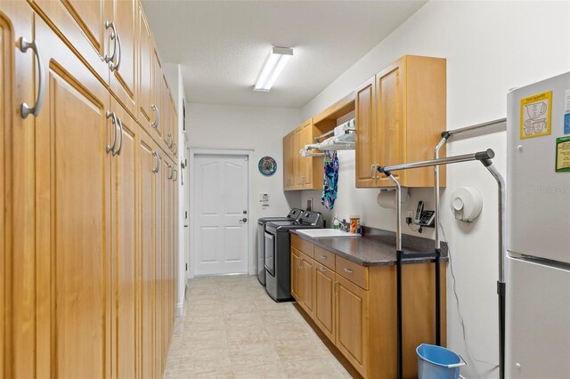 kitchen with a textured ceiling, fridge, and washer and clothes dryer