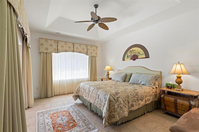 tiled bedroom with a raised ceiling and ceiling fan