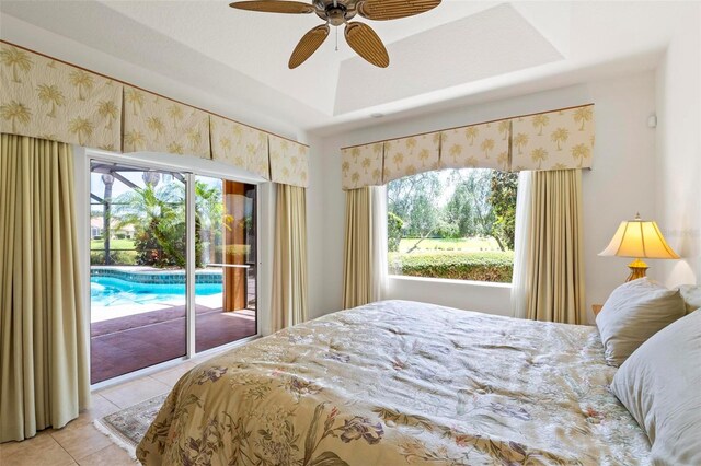 tiled bedroom with a tray ceiling, ceiling fan, and access to exterior