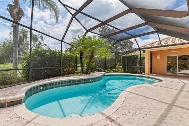 view of pool with ceiling fan, a patio, and glass enclosure