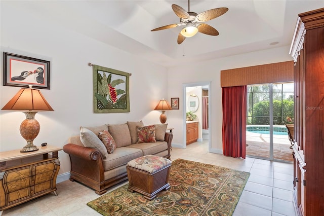 tiled living room featuring ceiling fan and a raised ceiling