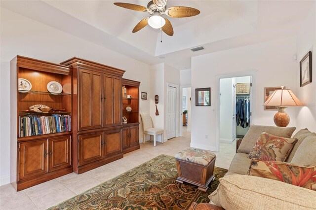 tiled living room with a raised ceiling and ceiling fan