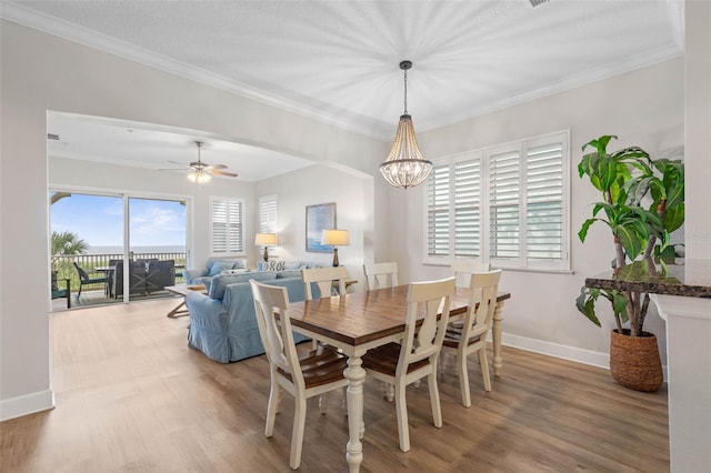 dining room featuring hardwood / wood-style flooring, ceiling fan with notable chandelier, and crown molding