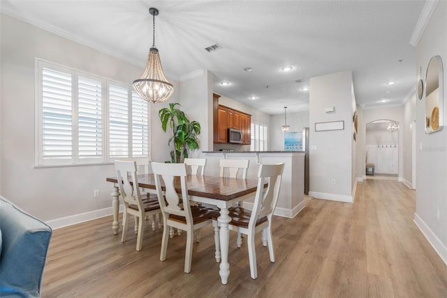 dining space featuring a notable chandelier, light wood-type flooring, and crown molding