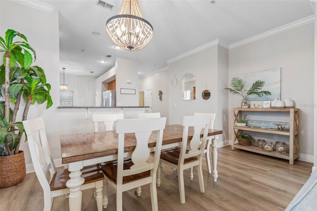 dining area with an inviting chandelier, light hardwood / wood-style flooring, and ornamental molding