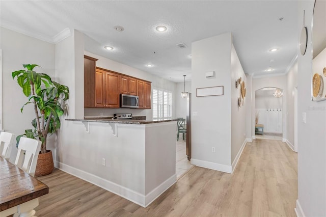 kitchen with light hardwood / wood-style floors, kitchen peninsula, hanging light fixtures, stainless steel appliances, and stone countertops