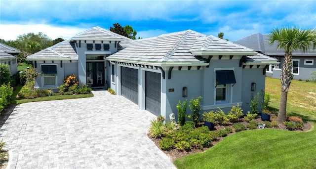 bungalow-style house featuring an attached garage, a front yard, decorative driveway, and stucco siding