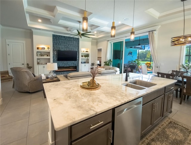 kitchen with a kitchen island with sink, a large fireplace, stainless steel dishwasher, sink, and ceiling fan