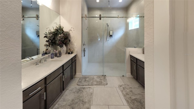 bathroom with a shower with door, vanity, and tile patterned floors