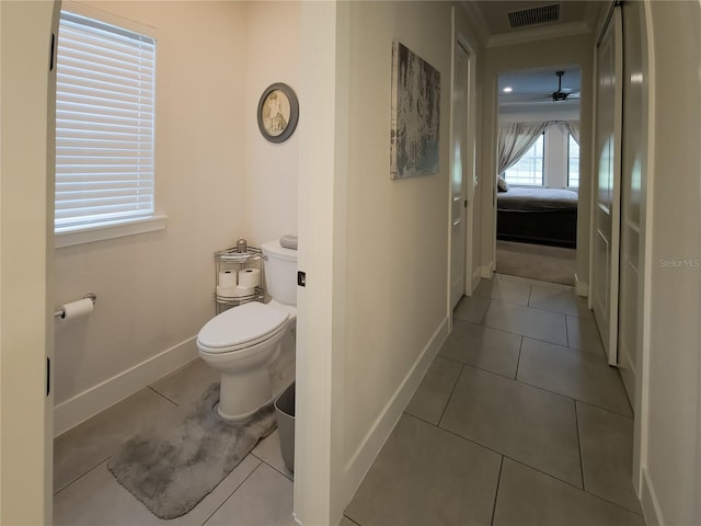 bathroom featuring toilet, baseboards, visible vents, ceiling fan, and ornamental molding