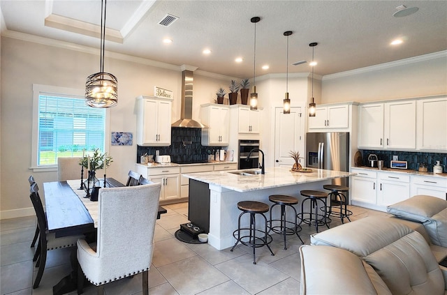 kitchen with decorative backsplash, visible vents, appliances with stainless steel finishes, and wall chimney range hood