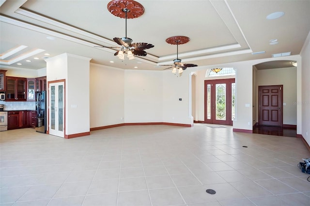 interior space featuring a tray ceiling, ornamental molding, light tile patterned flooring, and ceiling fan