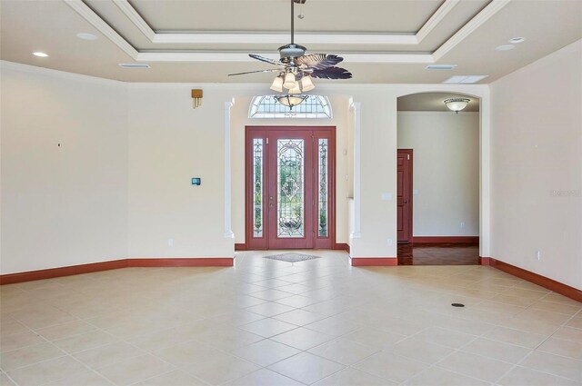 foyer entrance featuring ceiling fan, ornamental molding, a tray ceiling, and light tile patterned flooring