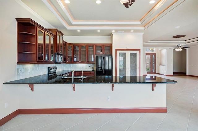 kitchen featuring a raised ceiling, kitchen peninsula, stainless steel appliances, and ceiling fan