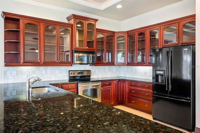 kitchen featuring appliances with stainless steel finishes, crown molding, sink, decorative backsplash, and dark stone countertops