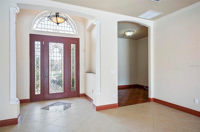 tiled entrance foyer featuring ornamental molding and ornate columns