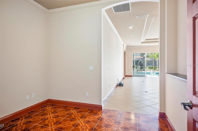 hallway with a textured ceiling, crown molding, and tile patterned floors