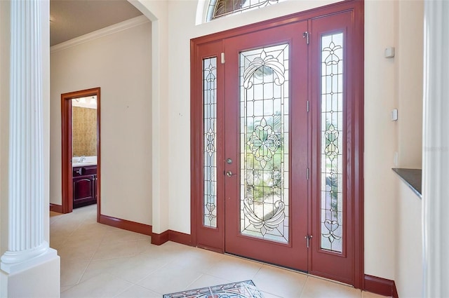 tiled entryway featuring crown molding and ornate columns