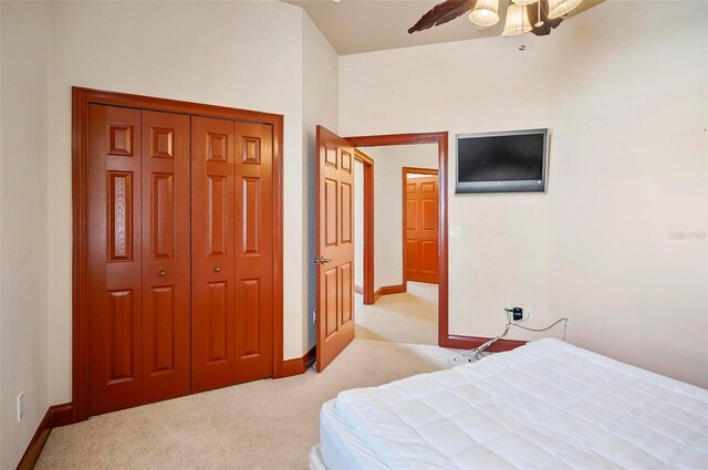 bedroom with a closet, ceiling fan, and light colored carpet