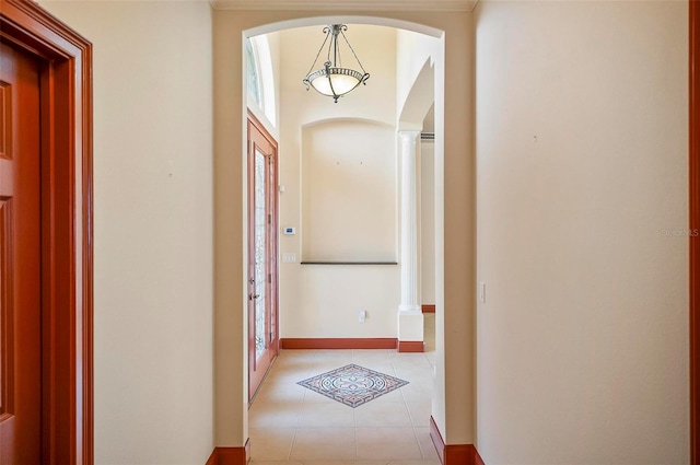 hall with plenty of natural light, light tile patterned floors, and decorative columns