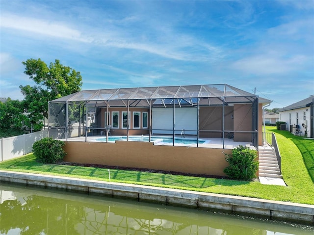 back of house with a water view, a yard, and glass enclosure