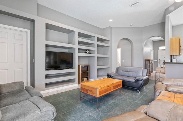 living room with built in shelves, a high ceiling, and dark tile patterned flooring