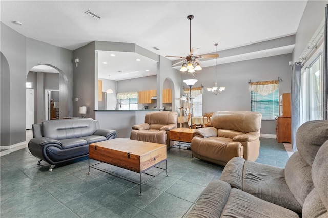 tiled living room with ceiling fan with notable chandelier