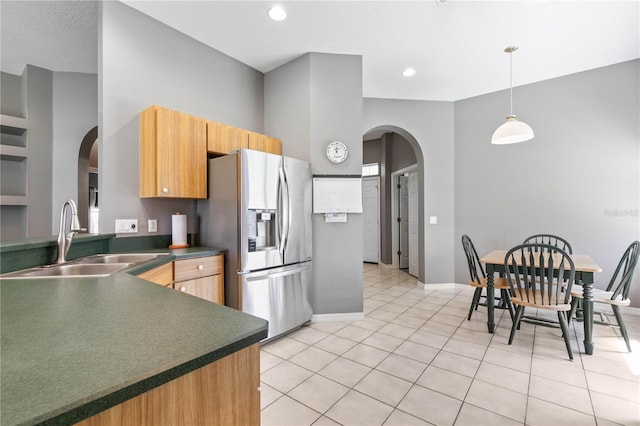 kitchen with hanging light fixtures, stainless steel fridge with ice dispenser, light tile patterned flooring, and sink