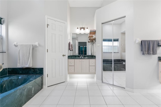 bathroom with tile patterned flooring, vanity, and a relaxing tiled tub