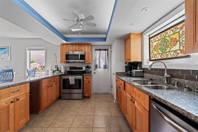 kitchen featuring a tray ceiling, light tile patterned flooring, sink, appliances with stainless steel finishes, and ceiling fan