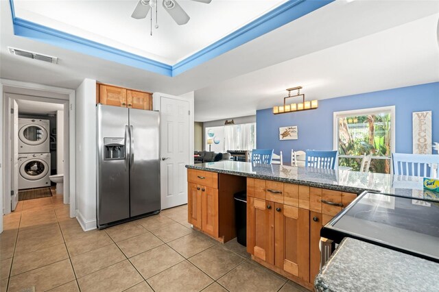 kitchen featuring hanging light fixtures, light tile patterned floors, stacked washer / drying machine, ceiling fan, and stainless steel fridge with ice dispenser