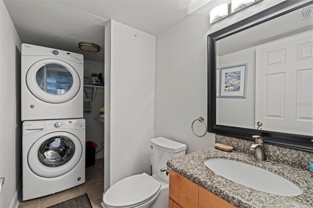 bathroom featuring tile patterned flooring, toilet, vanity, and stacked washing maching and dryer