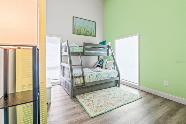 bedroom with light hardwood / wood-style flooring and a towering ceiling