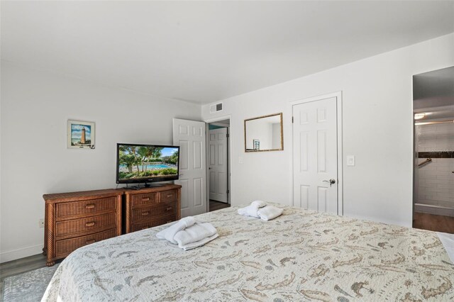 bedroom with wood-type flooring and ensuite bath