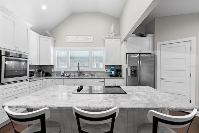 kitchen featuring a kitchen bar, stainless steel appliances, decorative backsplash, and white cabinets