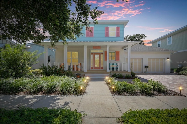 view of front of house featuring a garage, a porch, and decorative driveway