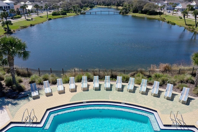 pool featuring a water view, a patio area, and fence