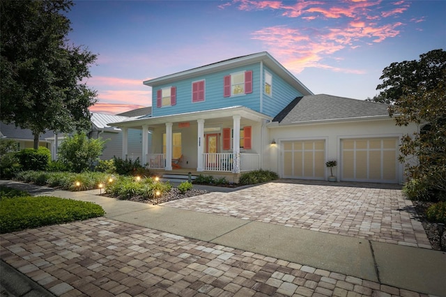 view of front of house featuring covered porch, decorative driveway, a garage, and stucco siding