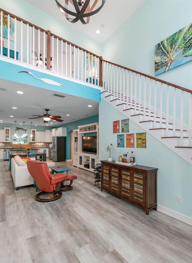 interior space with a high ceiling, ceiling fan, and light hardwood / wood-style floors