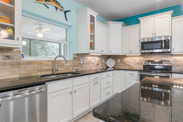 kitchen with dark stone counters, white cabinetry, stainless steel appliances, and sink