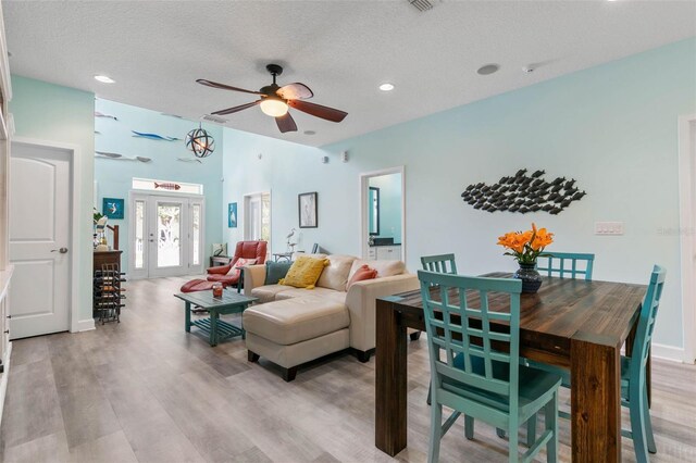 living room featuring light wood-type flooring, ceiling fan, and a textured ceiling