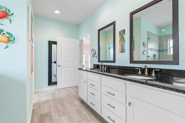 bathroom with vanity, a tile shower, and wood-type flooring