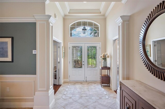 entrance foyer featuring ornamental molding, french doors, plenty of natural light, and ornate columns