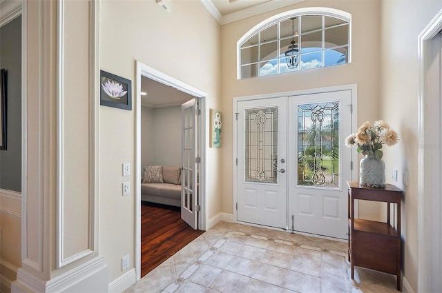 entryway with french doors, a high ceiling, light hardwood / wood-style floors, and ornamental molding